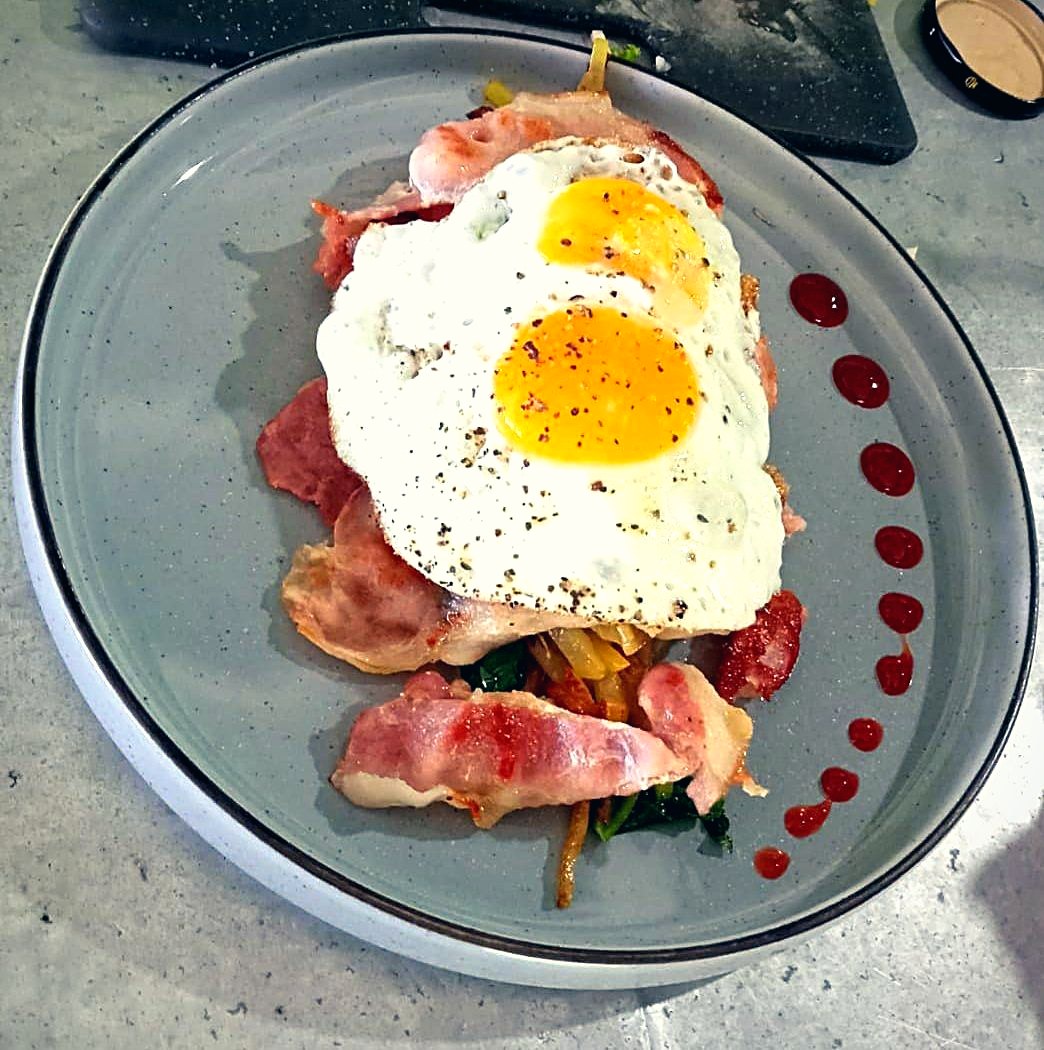 Breakfast of eggs and bacon plated with fresh garnish