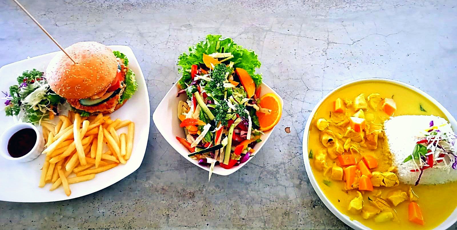 Burger with fresh salad and a fruit bowl